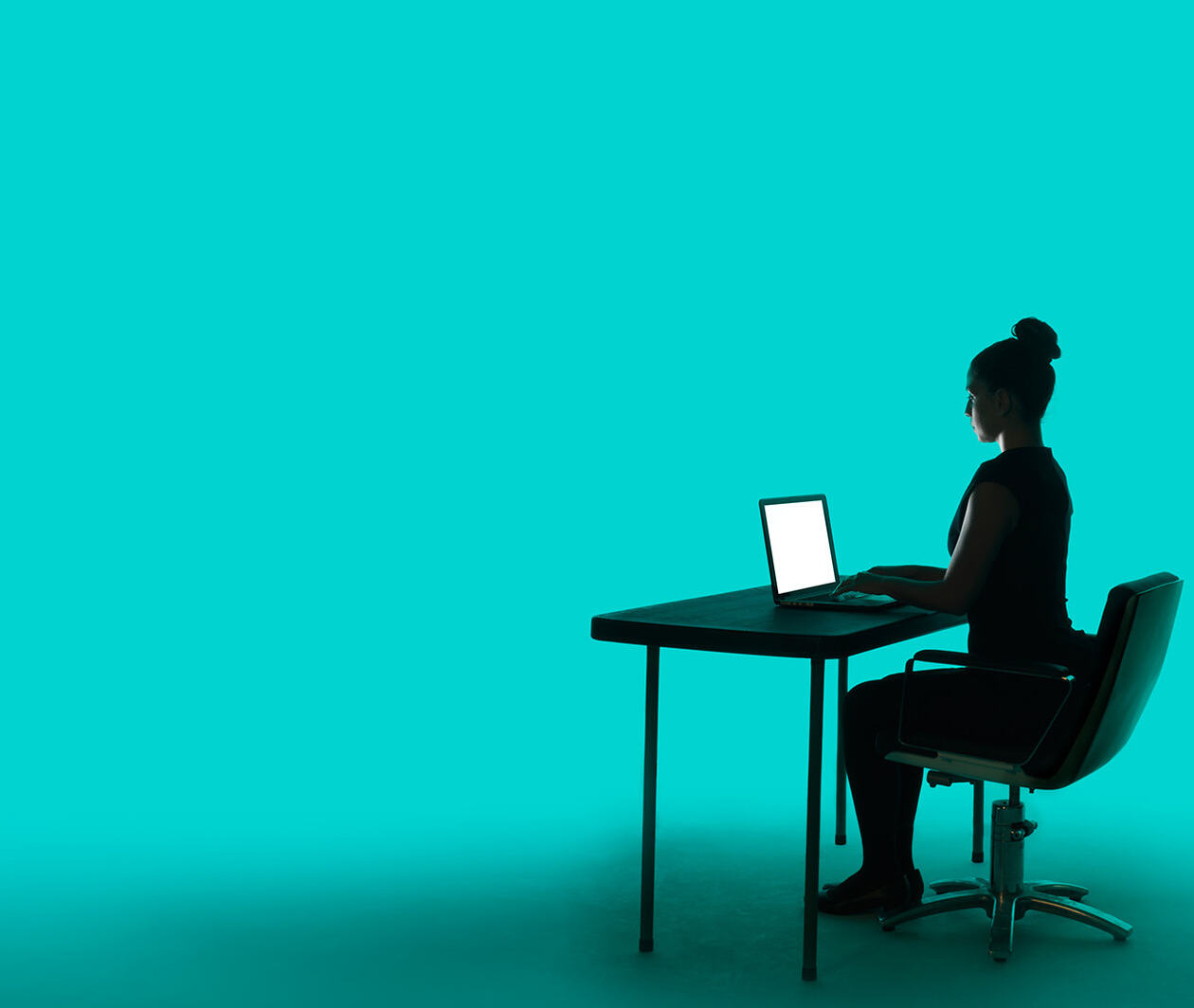 A woman sits at a desk on a computer with a blue background.