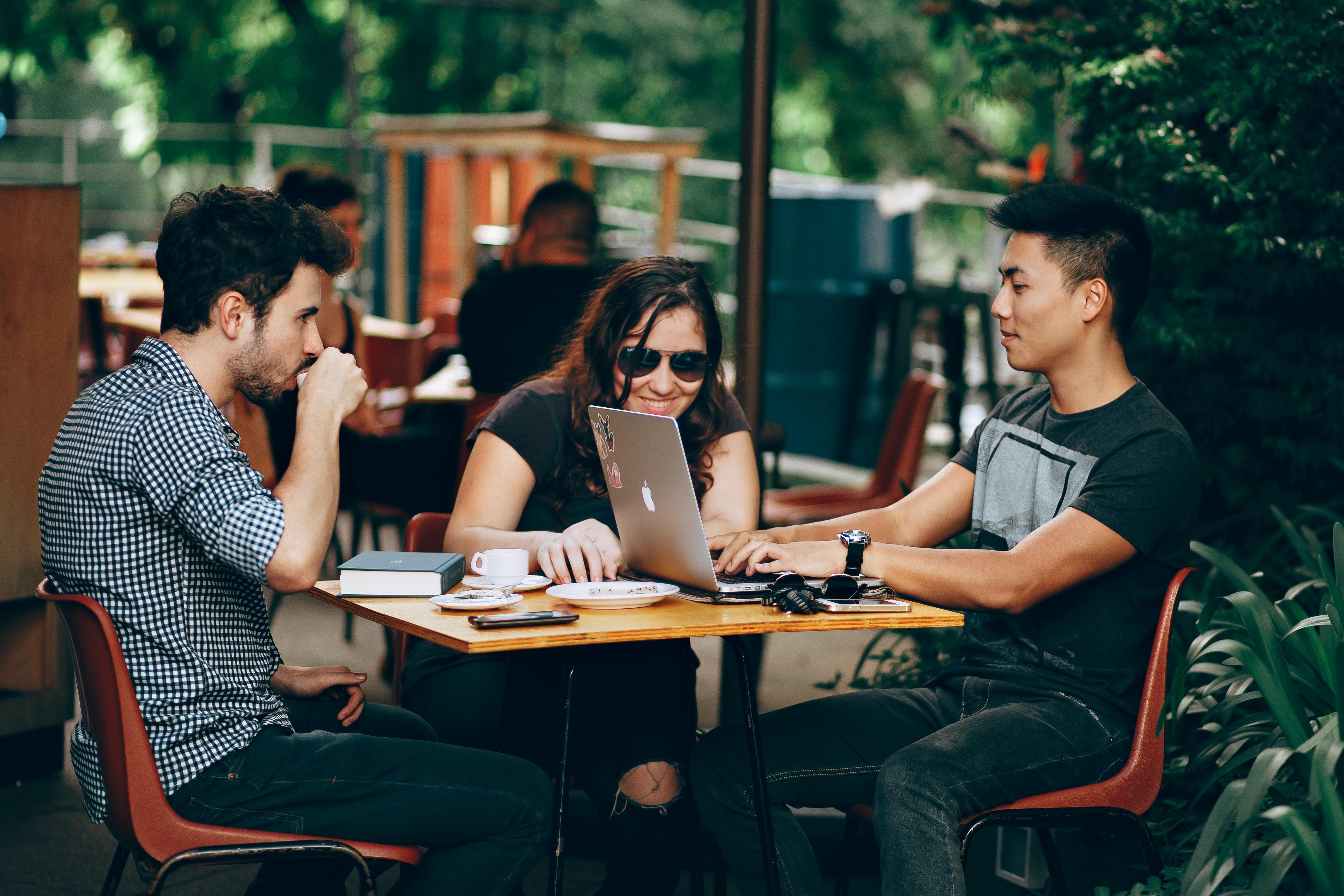 3 students sitting at cafe with laptops