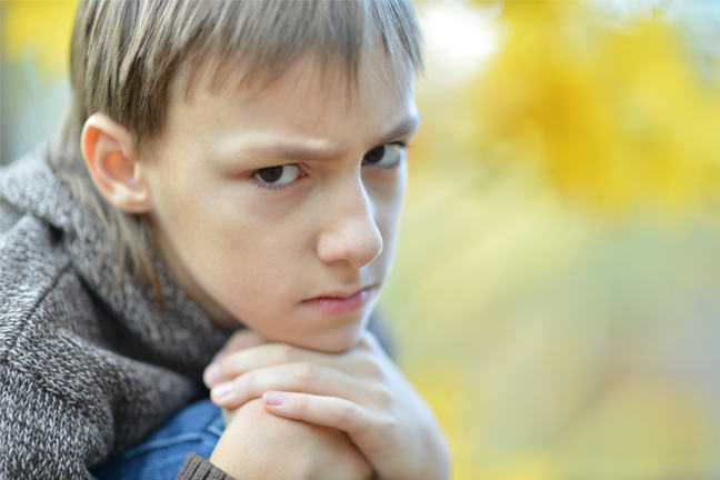 Sad boy holding a hand to his cheek