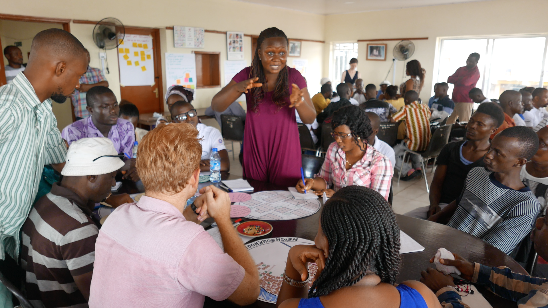 A woman addressing a group of people sat around a table in a classroom.