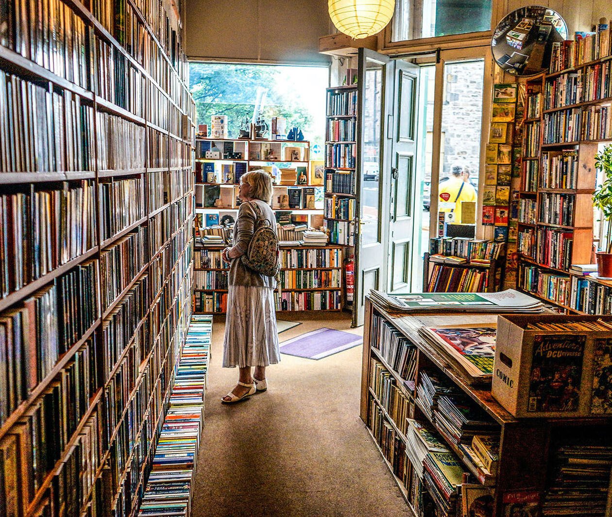 A woman in a bookshop in Edinburgh, staring at the shelves. 