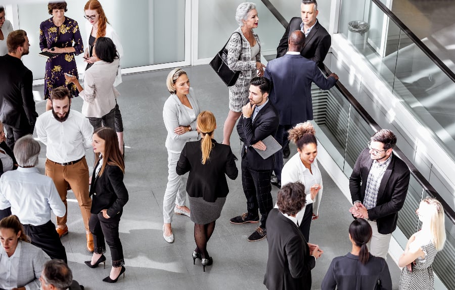 An aerial shot showing groups of people in business dress chatting.