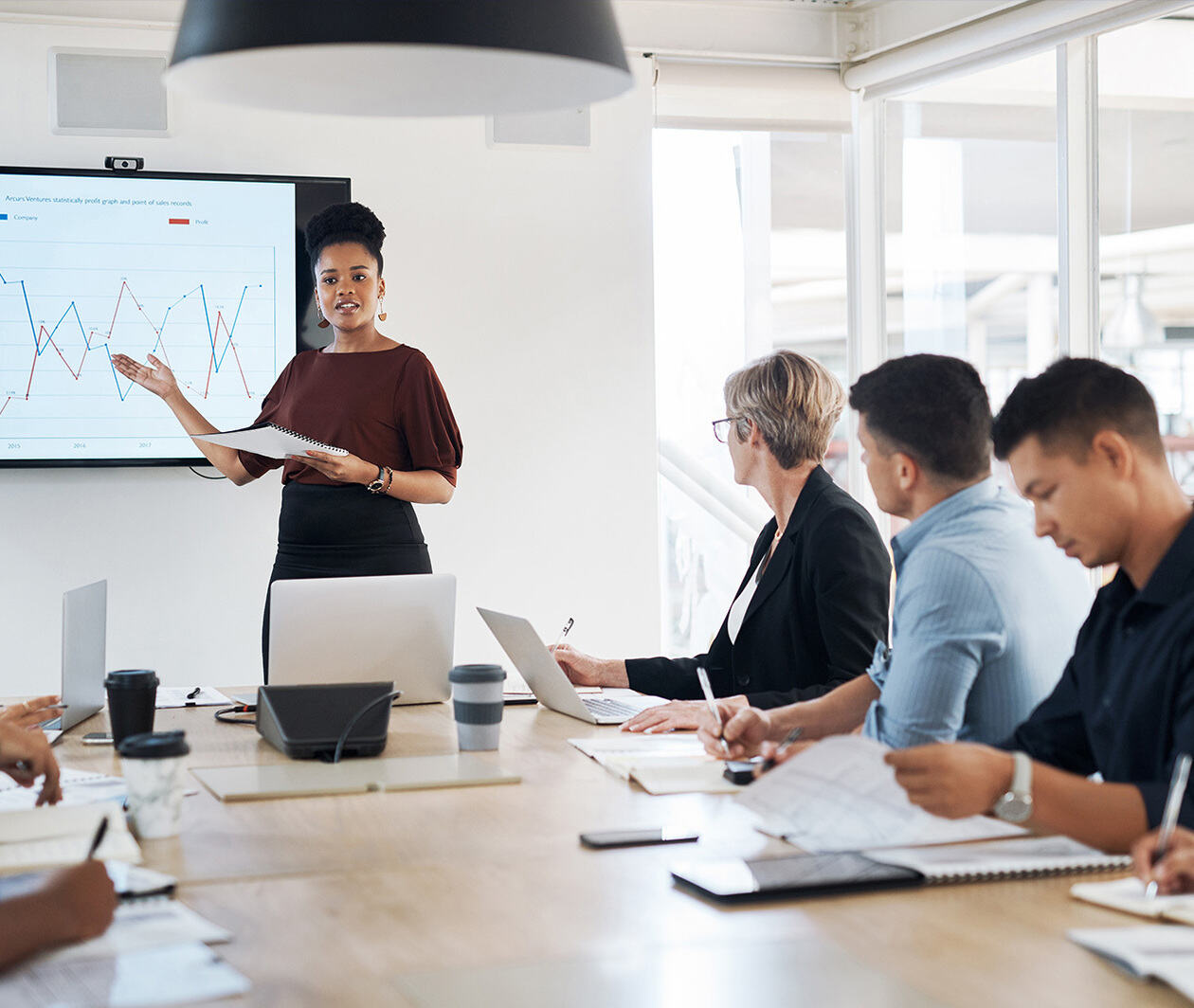 Board room presentation with charts on a screen