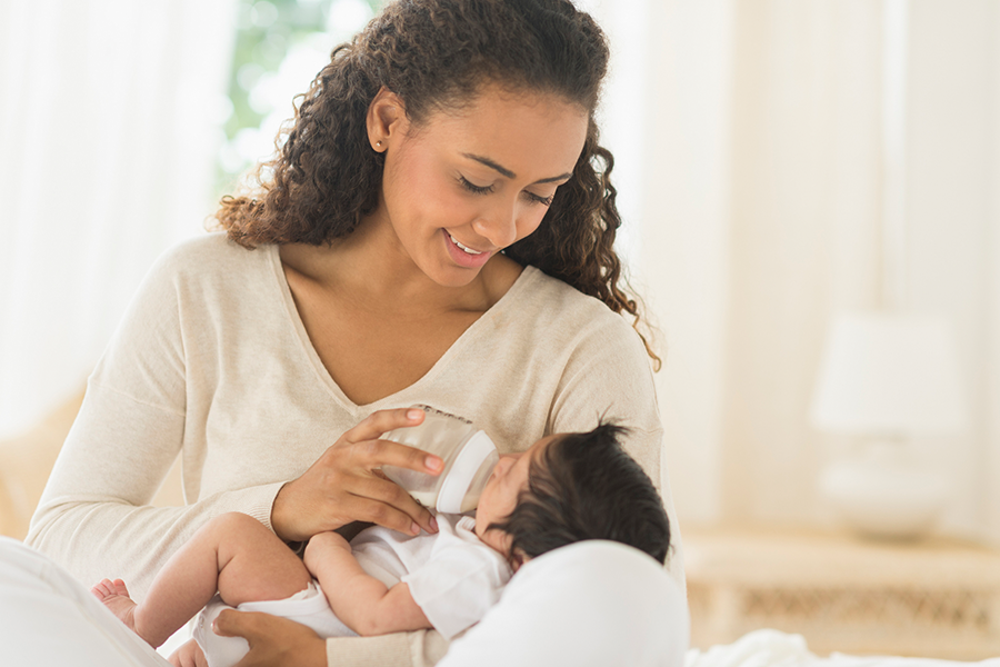 Hispanic mother feeding newborn baby