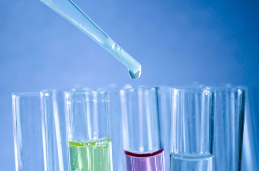 A pipette drips liquid into a test tube of coloured liquid