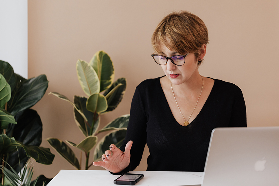 A woman sitting down at a table looking at something on her phone.