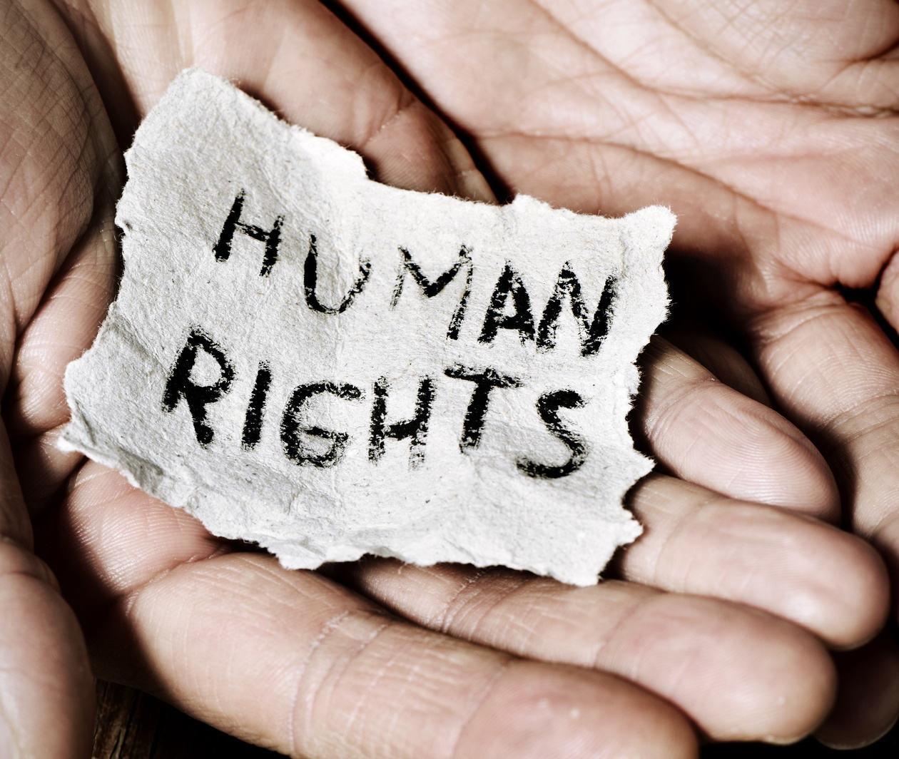 The inscription "human rights" written on a little piece of paper held between two hands 