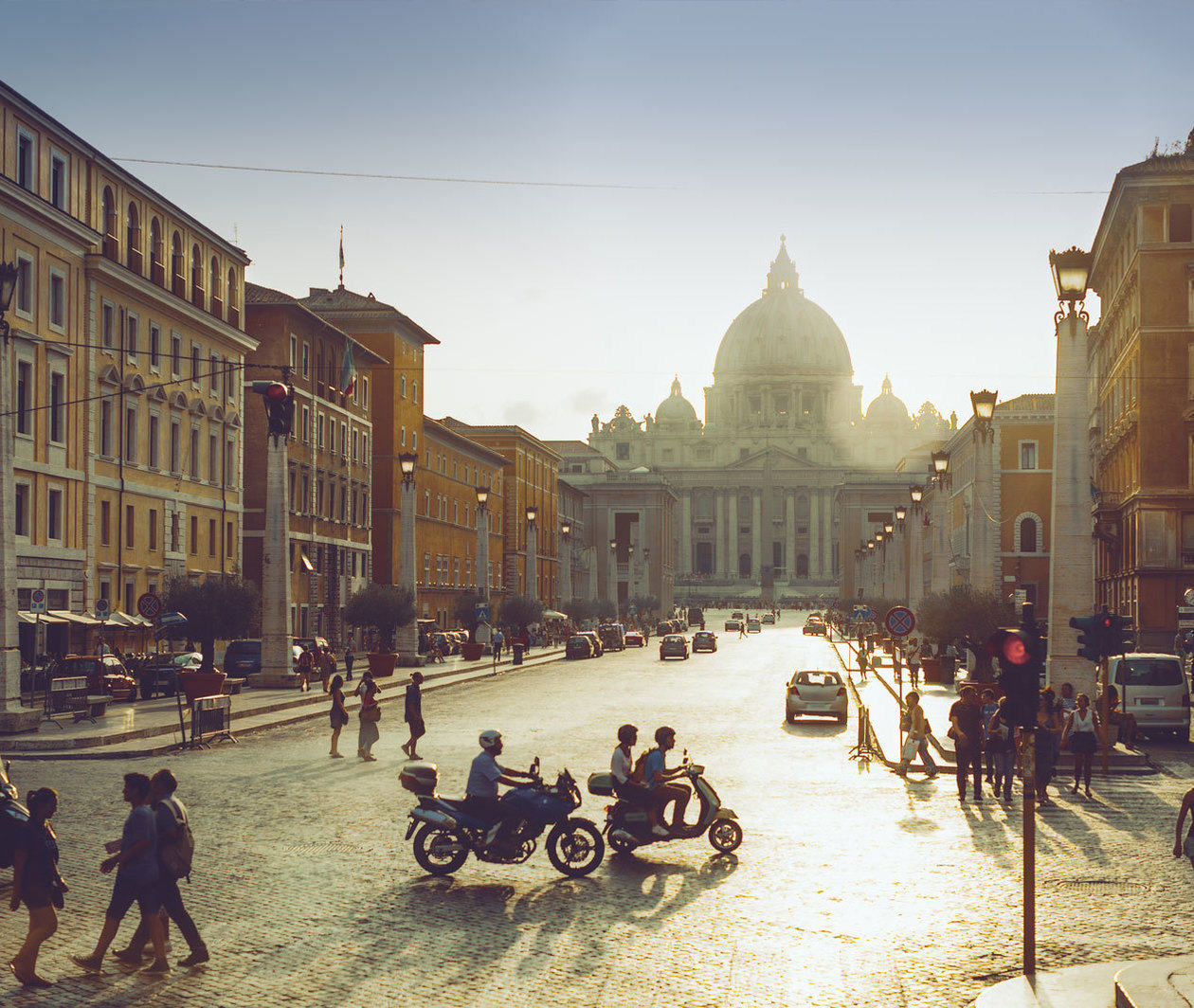 Photograph of a busy street in Rome with St. Peter's Basilica in the distance