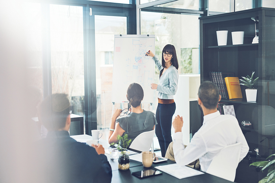 Transformations in industries are impacting the skills employers are looking for. An office environment with a women presenting information to her team.