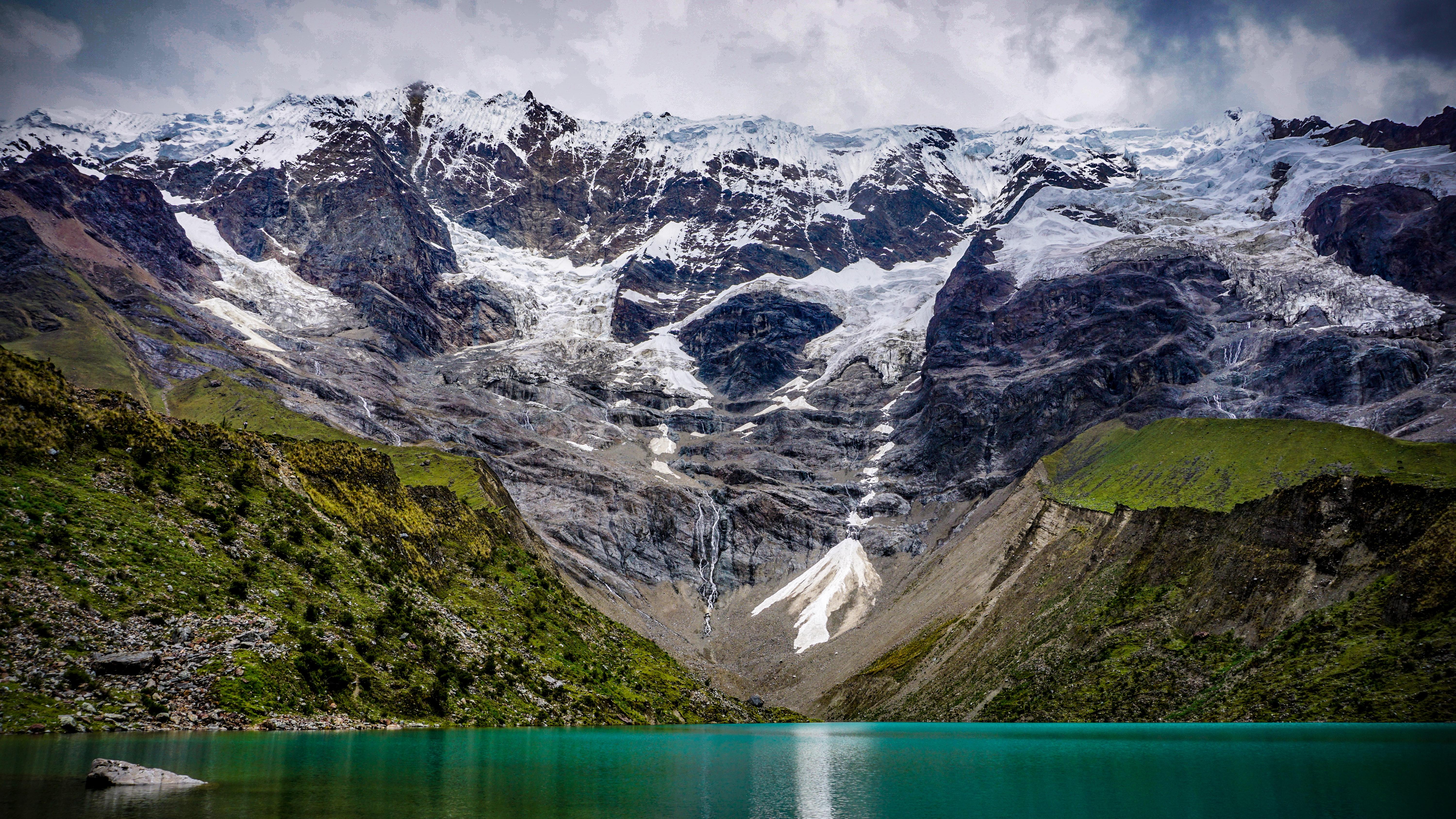 An image showing a series of glaciers and a turquoise proglacial lake in the foreground.