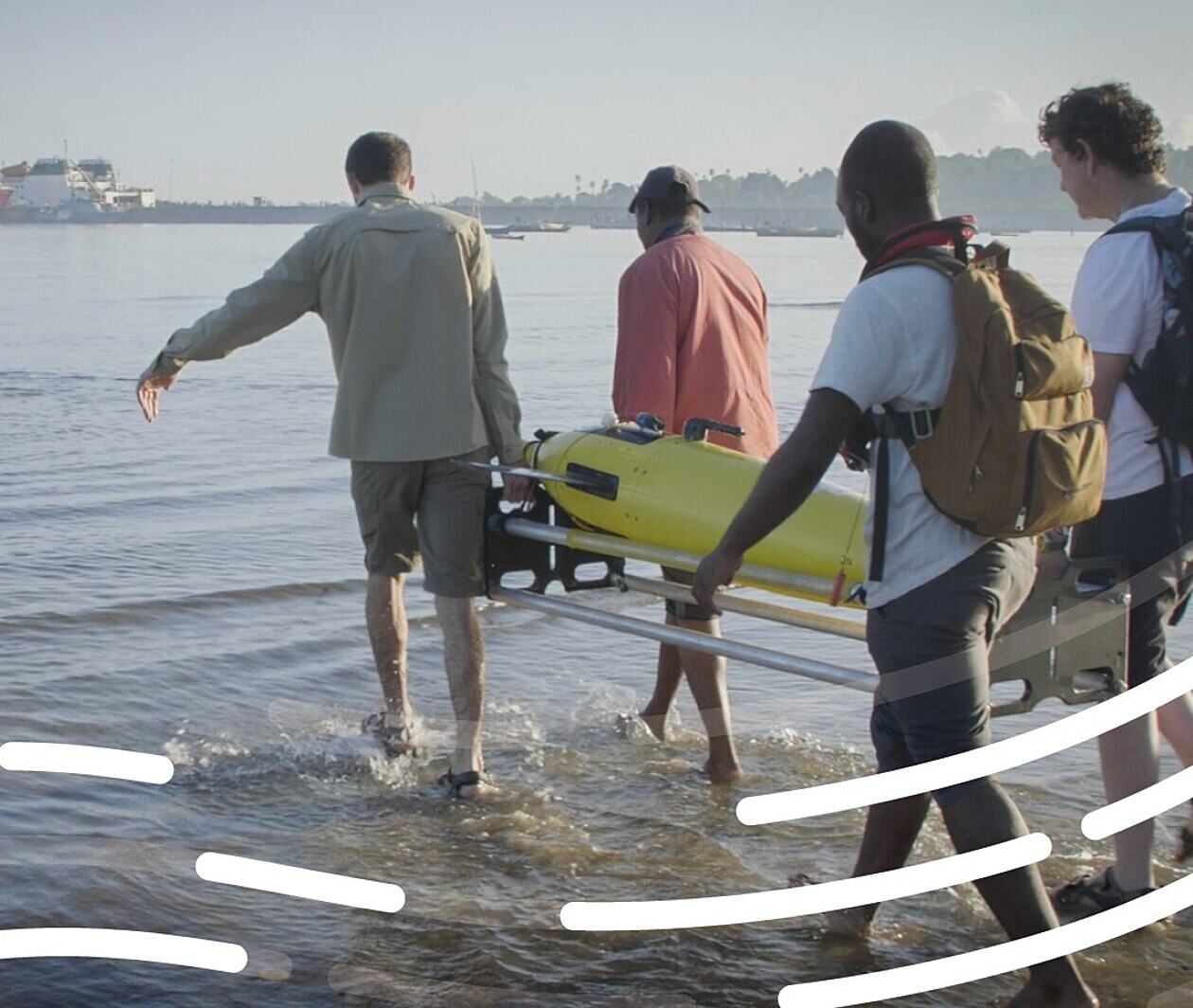 Marine scientists carrying ocean robot to the water 