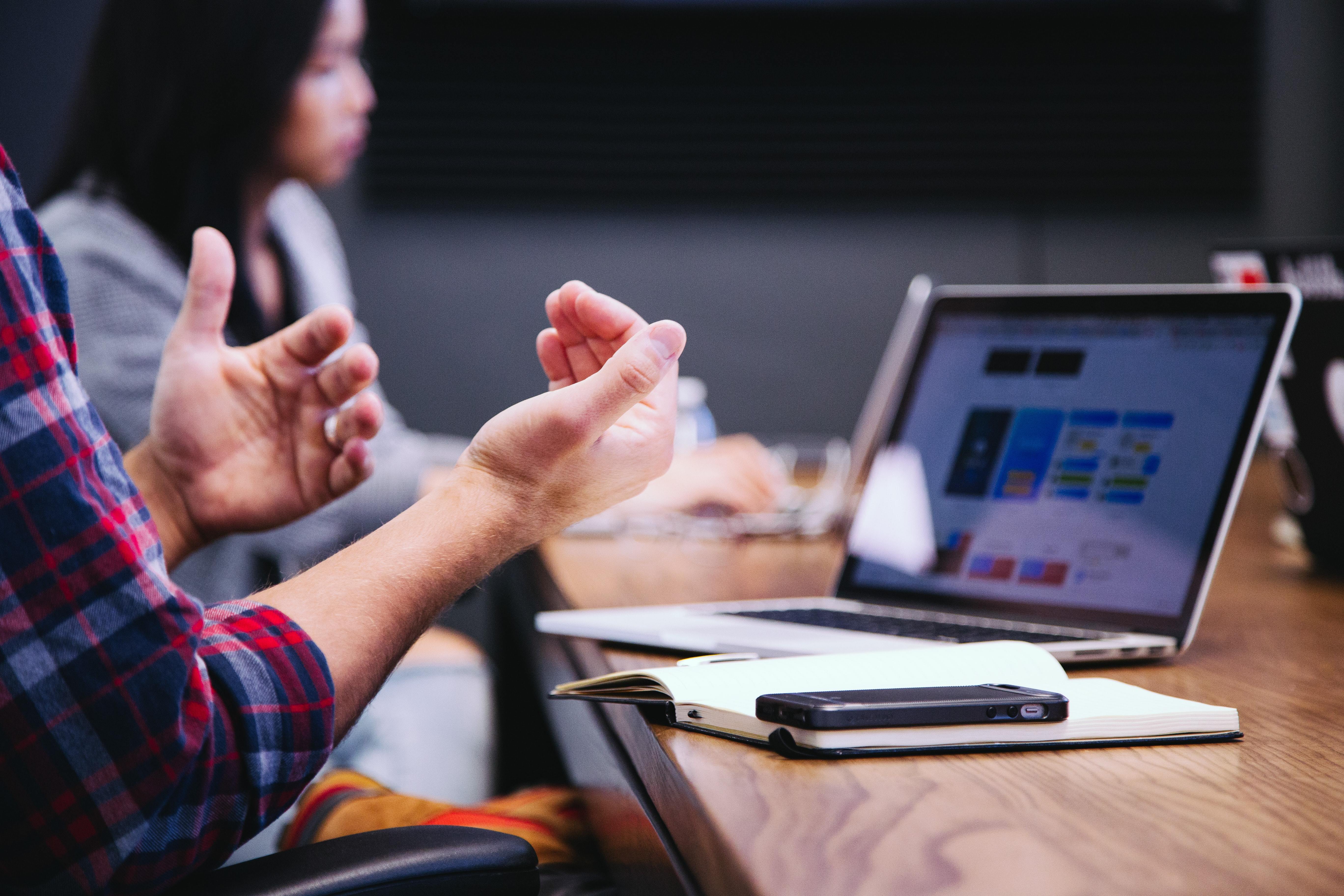 person using hands to illustrate their communication while speaking to a laptop screen