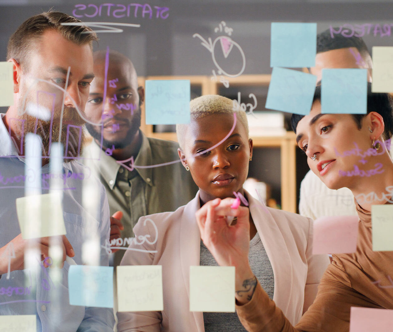 A group of colleagues gather around a post-it note board.