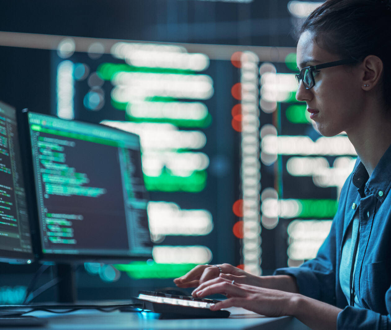 Woman coding on multiple computer screens