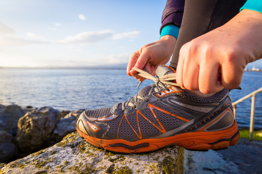 A picture of a person tying their shoelaces with the sea in the background.