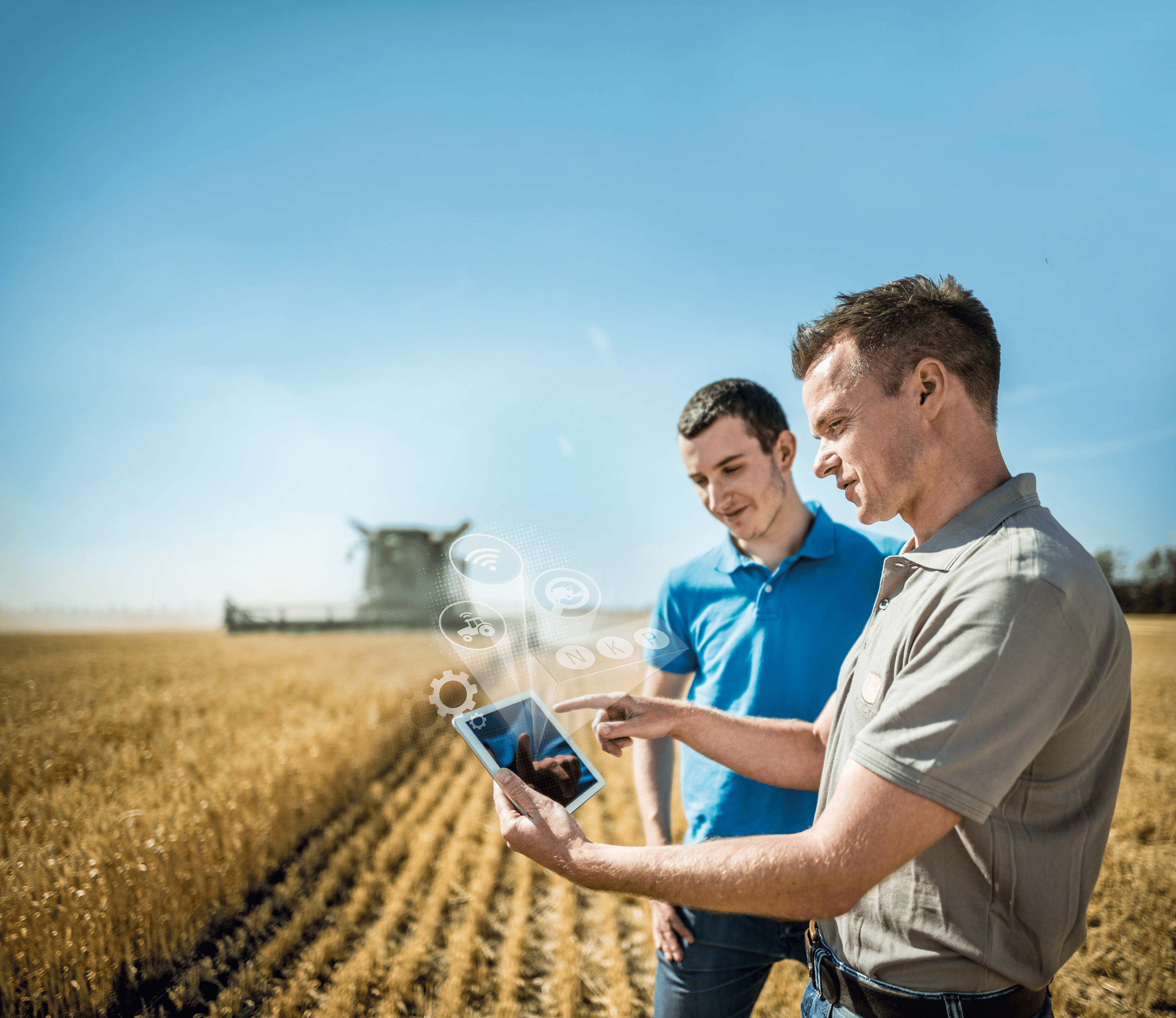 Two men stand in a field looking at a tablet