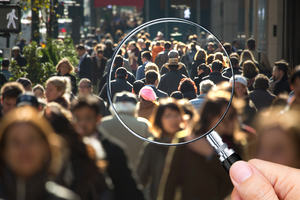 A handheld magnifying glass held over an image of people
