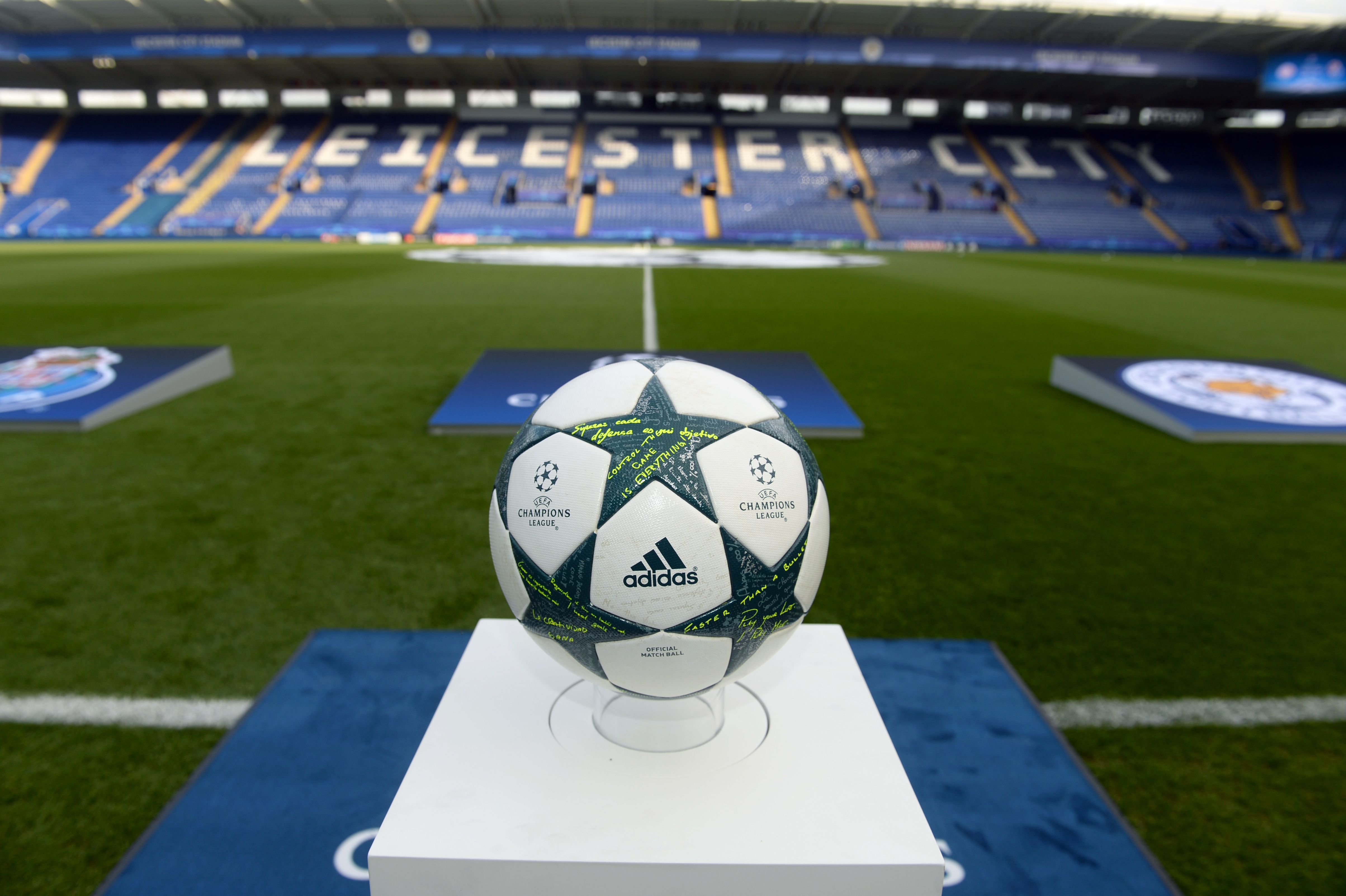 A Champions League football resting on a pedastal within an empty stadium.