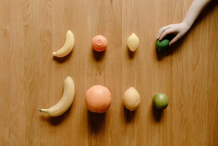 a smiley face made out of fruit on a table, pi-slices and kidmograph, kids talking to fruit people, shape language, playful composition