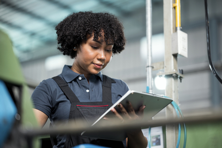 Quality Control in the Manufacturing Process. Female African American Quality Control Engineer is examining engineering workpiece by random visual check based on a quality standard check-sheet.