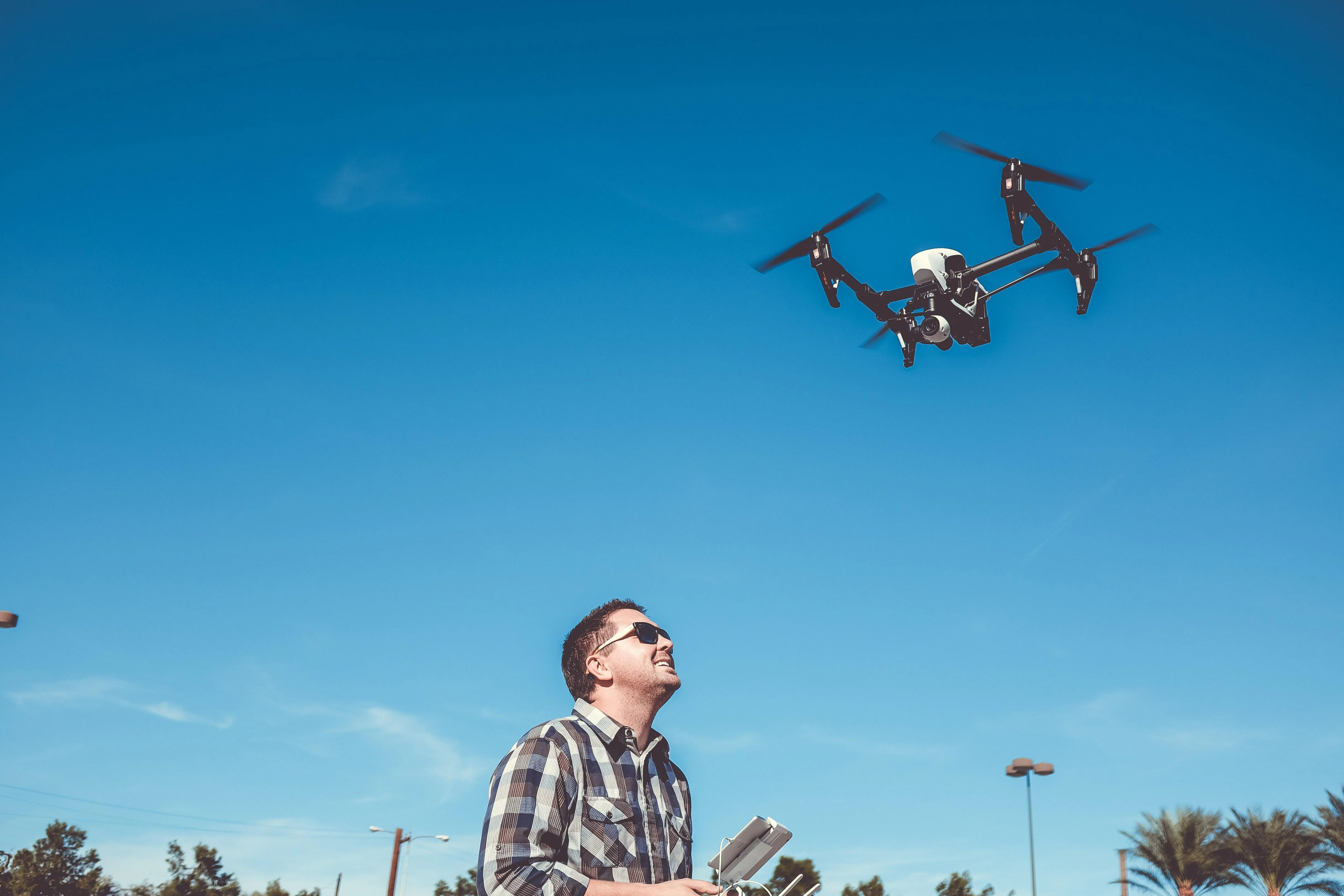 man flying a done against a blue sky