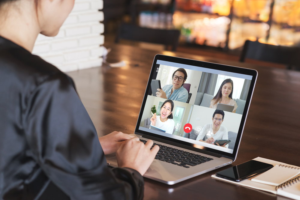 Woman sitting in front of a computer which is showing four other people on a conference call