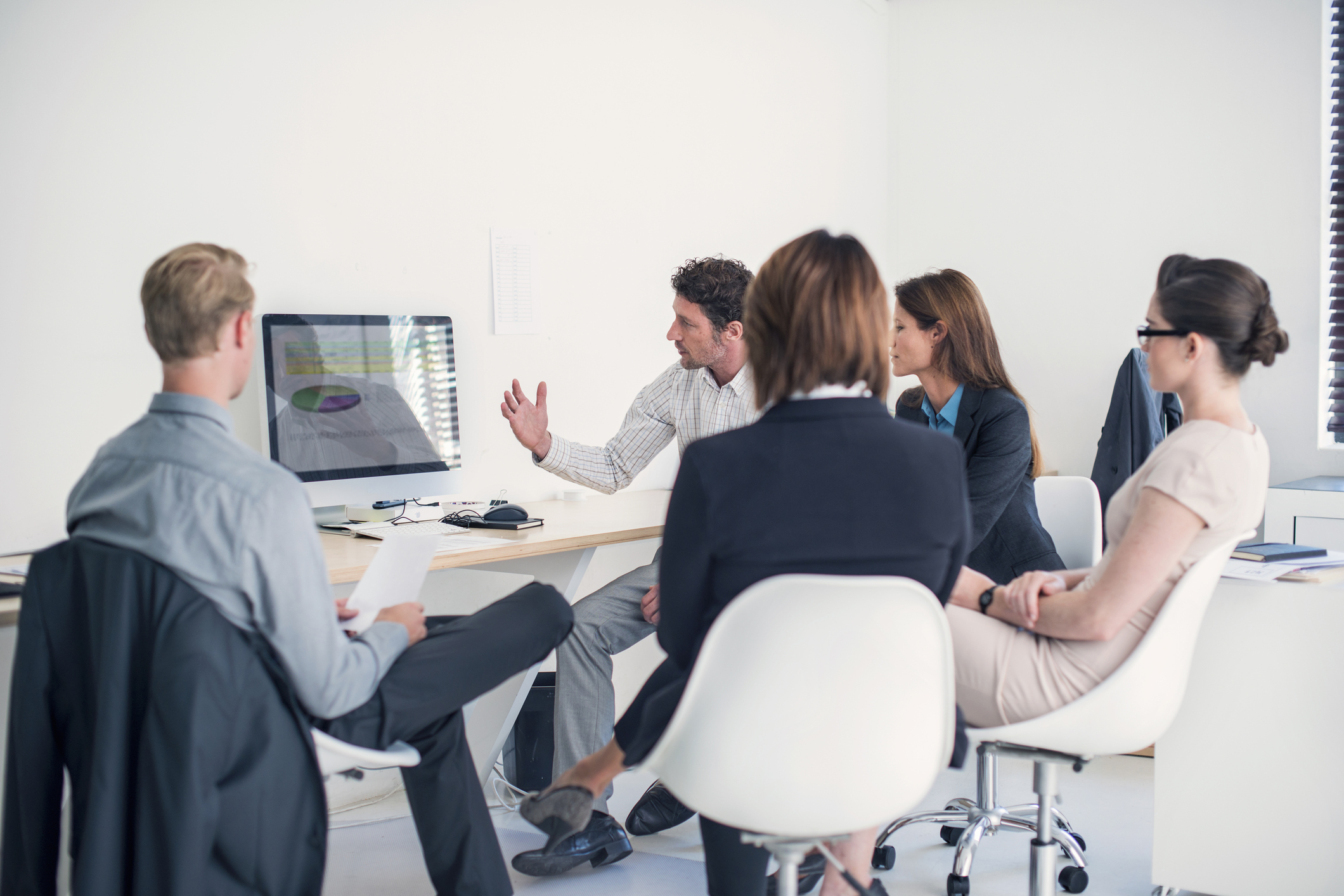 A group of people discussing data on screen