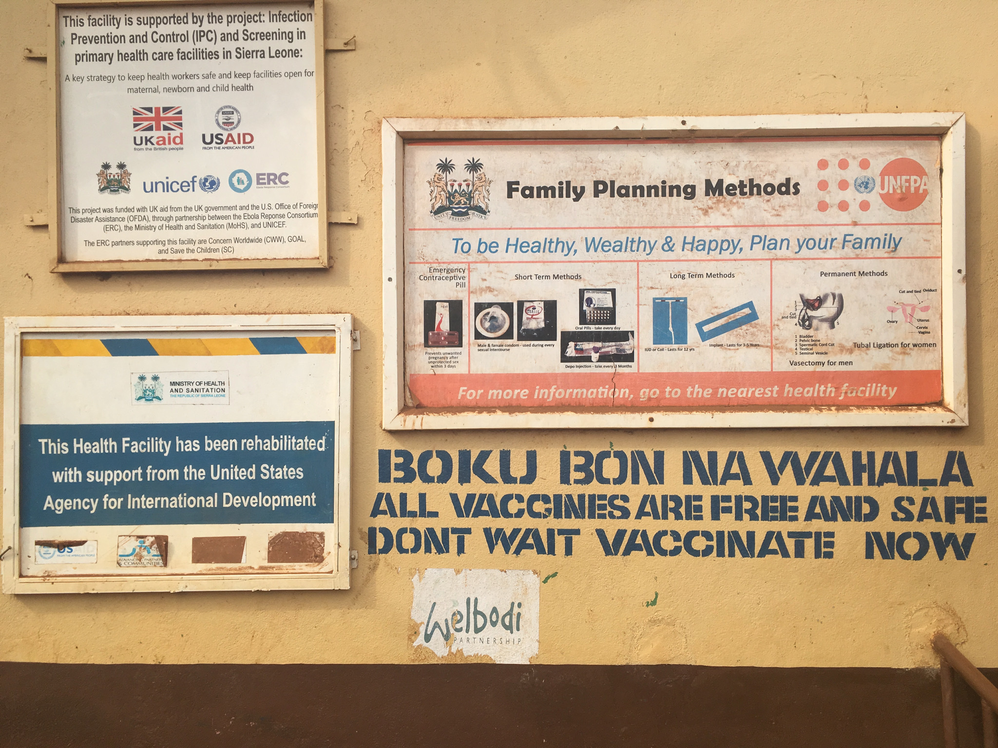 The wall of a health centre with signs, including one advising on available vaccinations