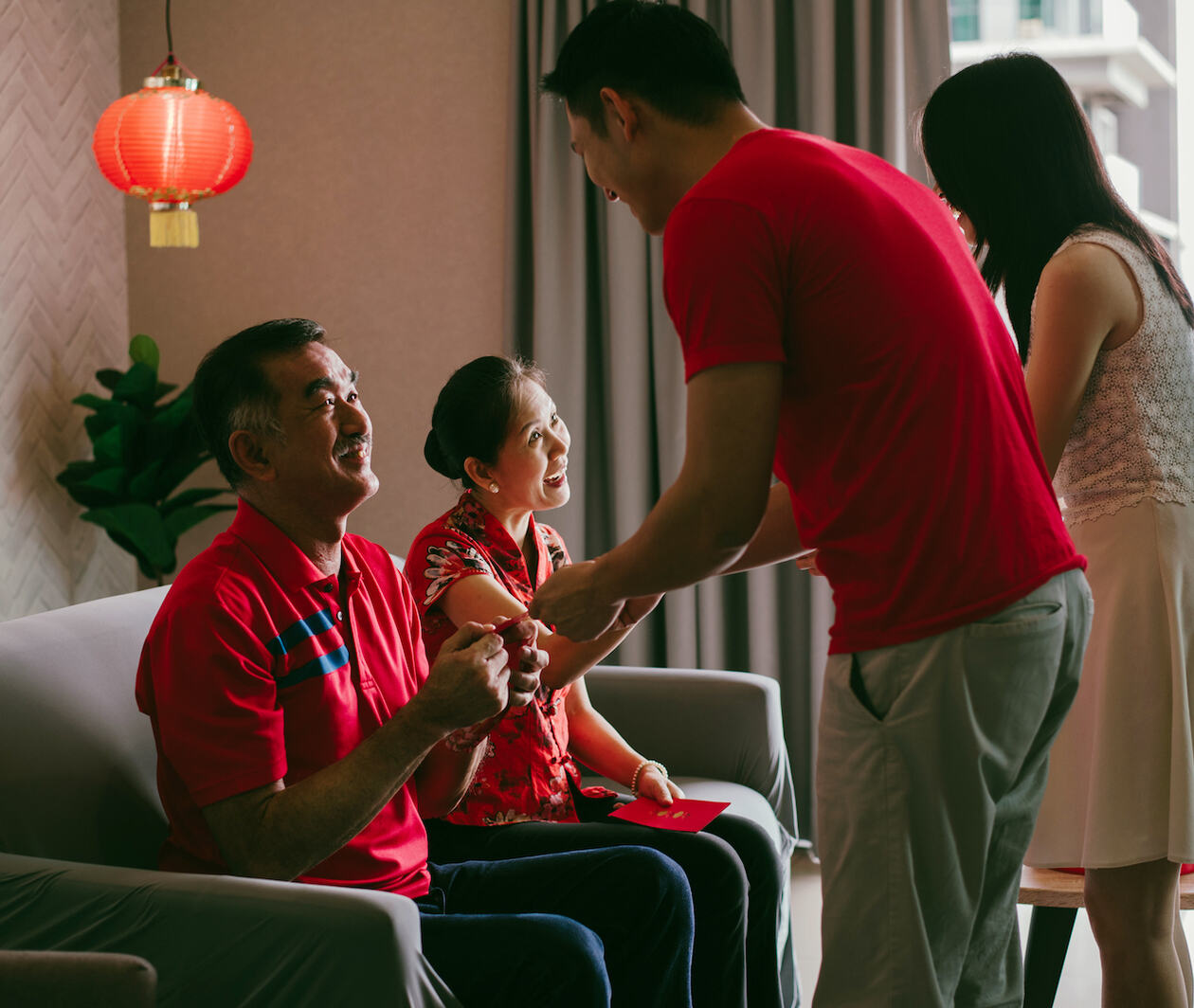 A younger Chinese man and woman presenting gifts to older Chinese man and woman