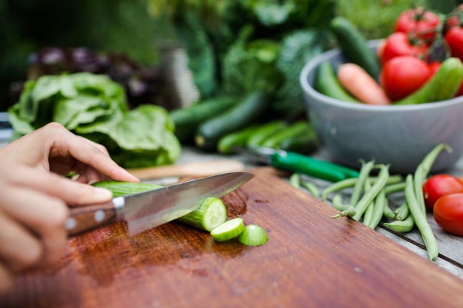 Cutting fresh vegetables on chopping board