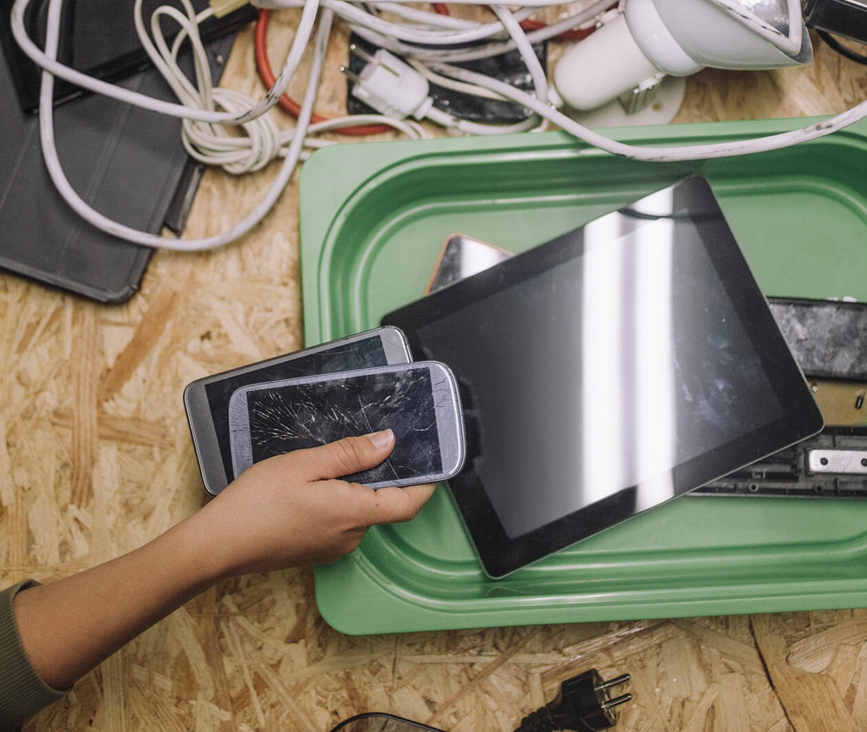 Directly above shot of a worker with old smart phone and tablets at table for recycling