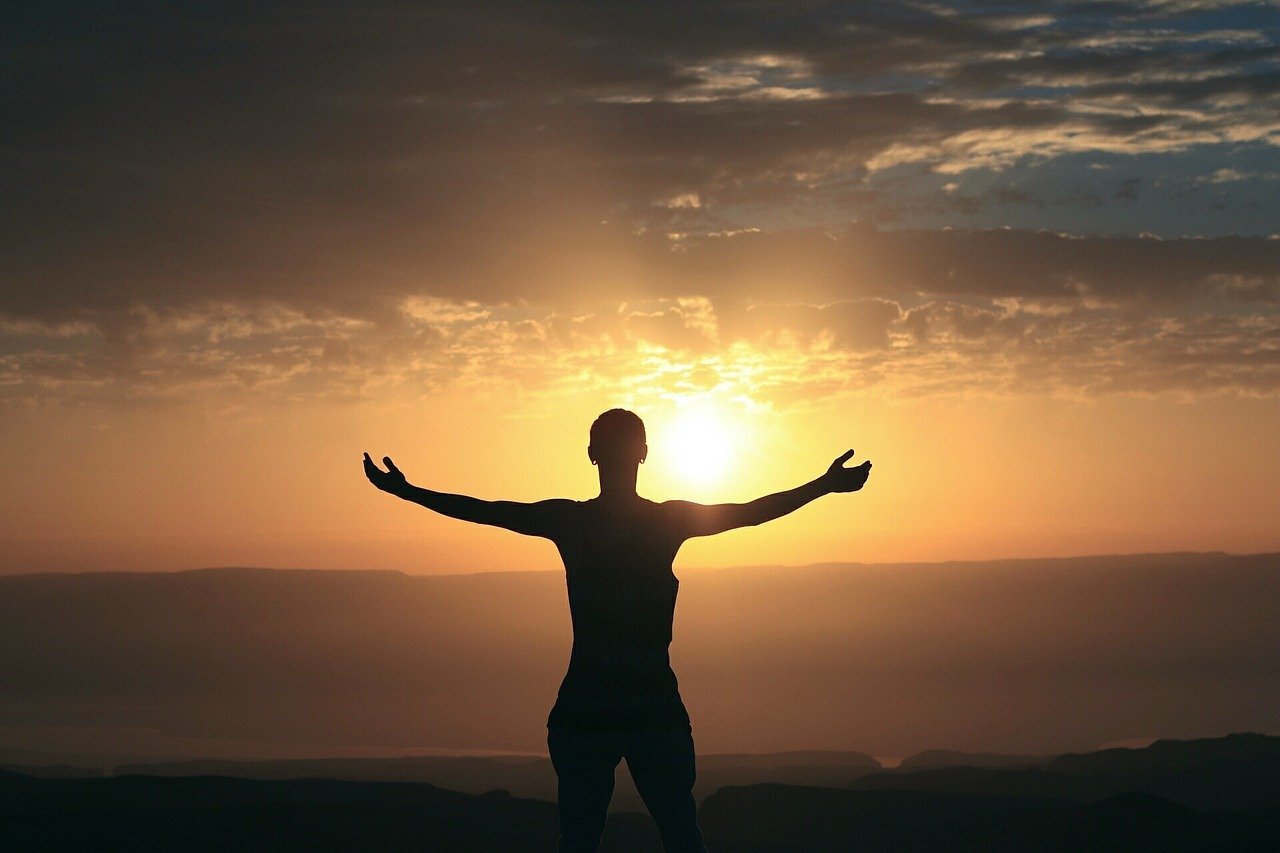 A silhouette of a woman looking at the sunrise.