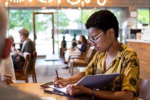 Female journalist writing up a news article for publication.