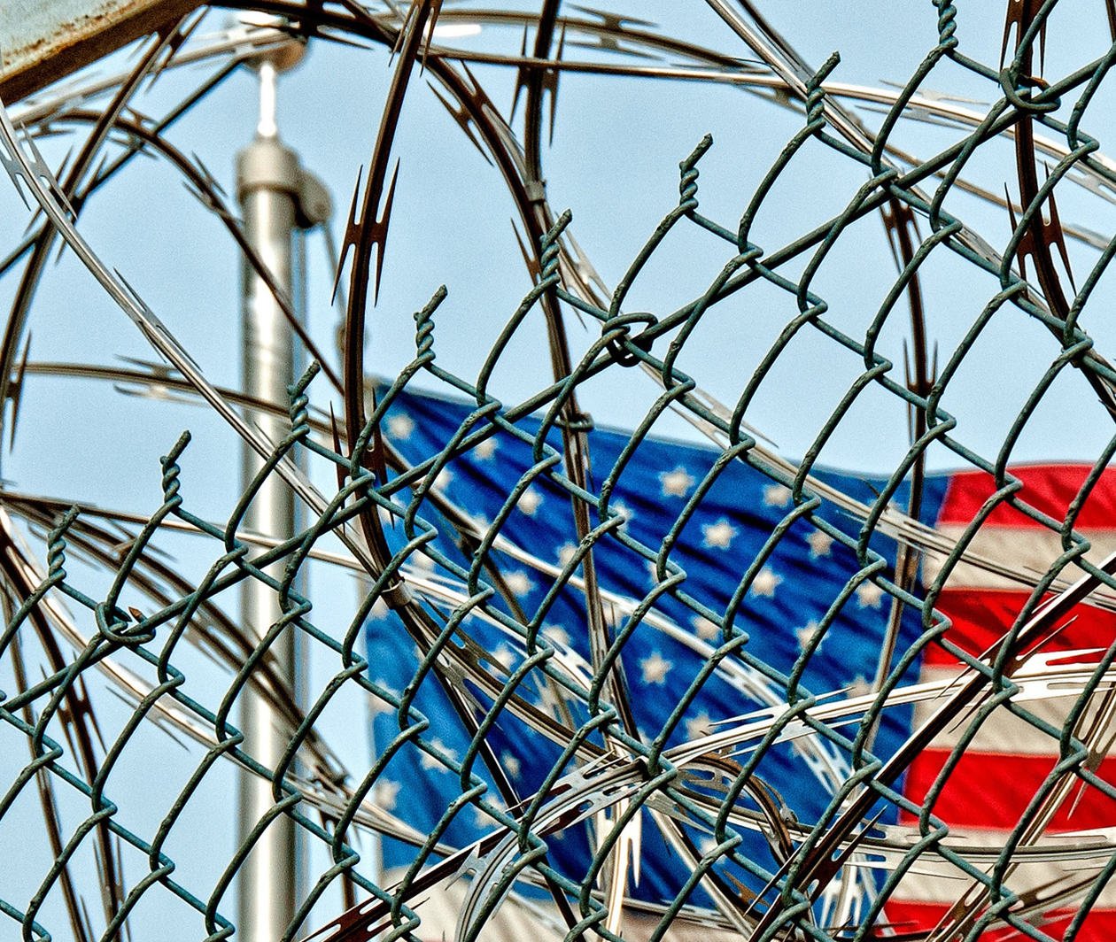 Prison detention fence with US flag in background