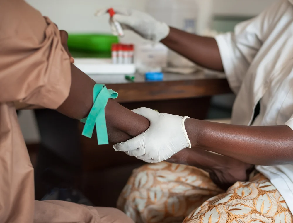 A healthworker taking a blood sample from a woman.