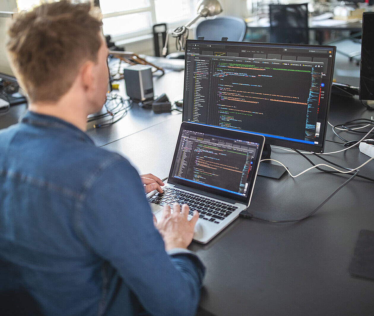 Man working at a computer with code on the screen