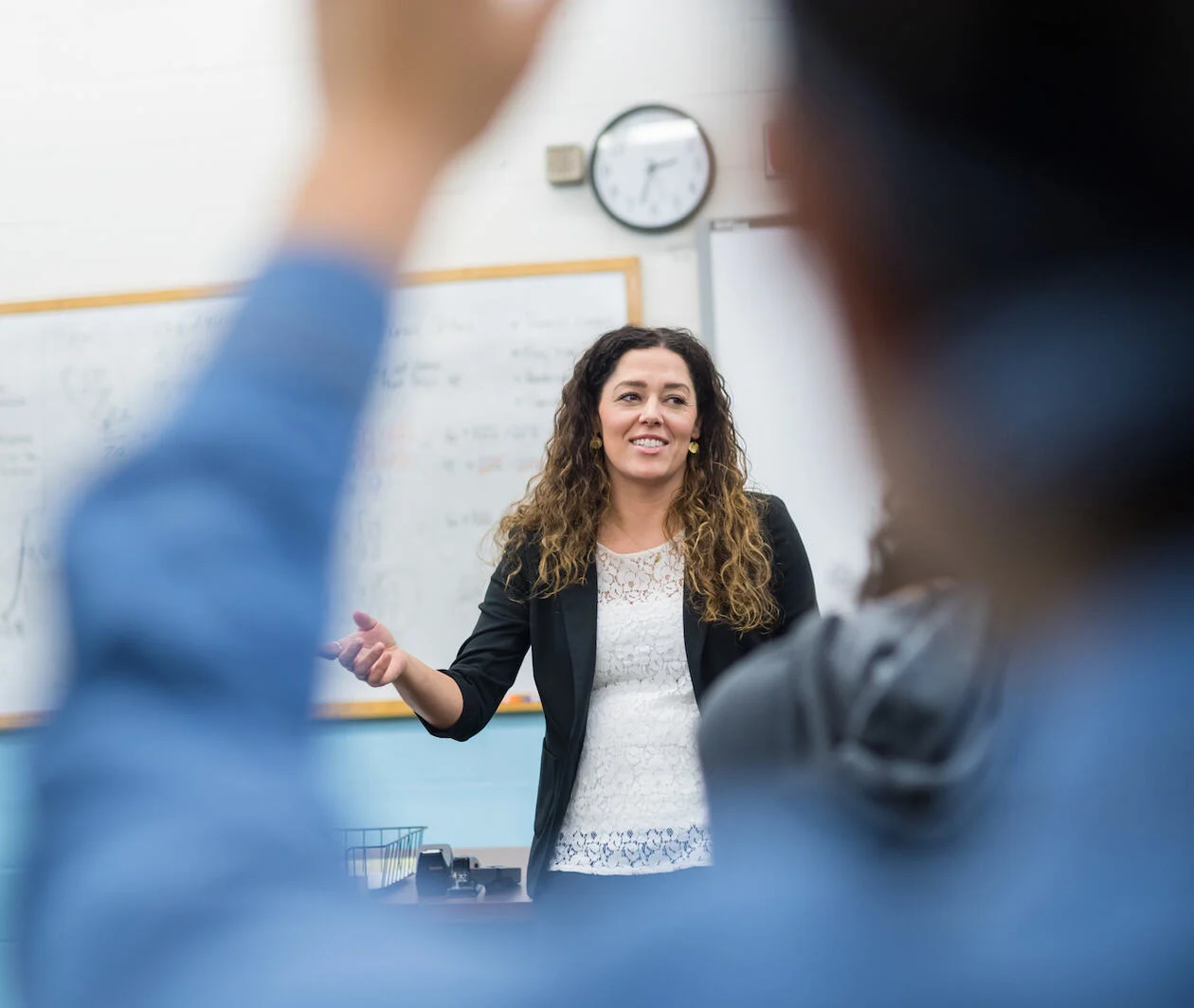 A female teacher standing at the front of a class, teaching mathematical concepts,  probability and statistics.