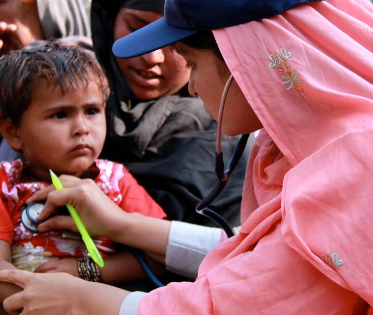 A female doctor with the International Medical Corps checking the heartbeat of a young boy with a stethoscope