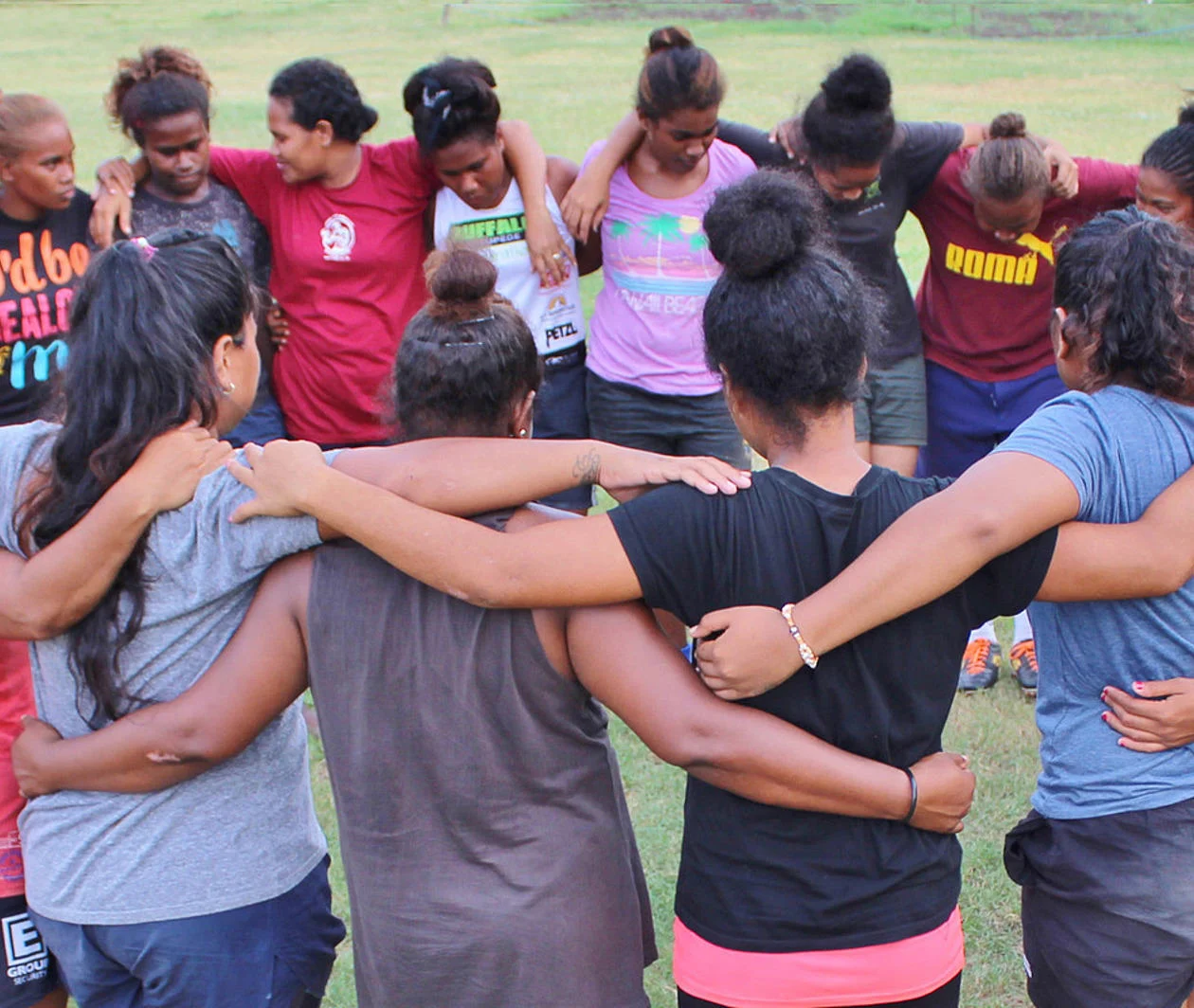 Girls connected in circle, linking arms around each others shoulders