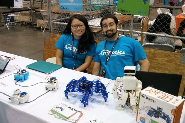 Two people at a table with robots