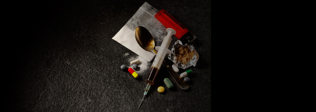 A syringe, spoon, lighter, pills and other items associated with drugs and addiction