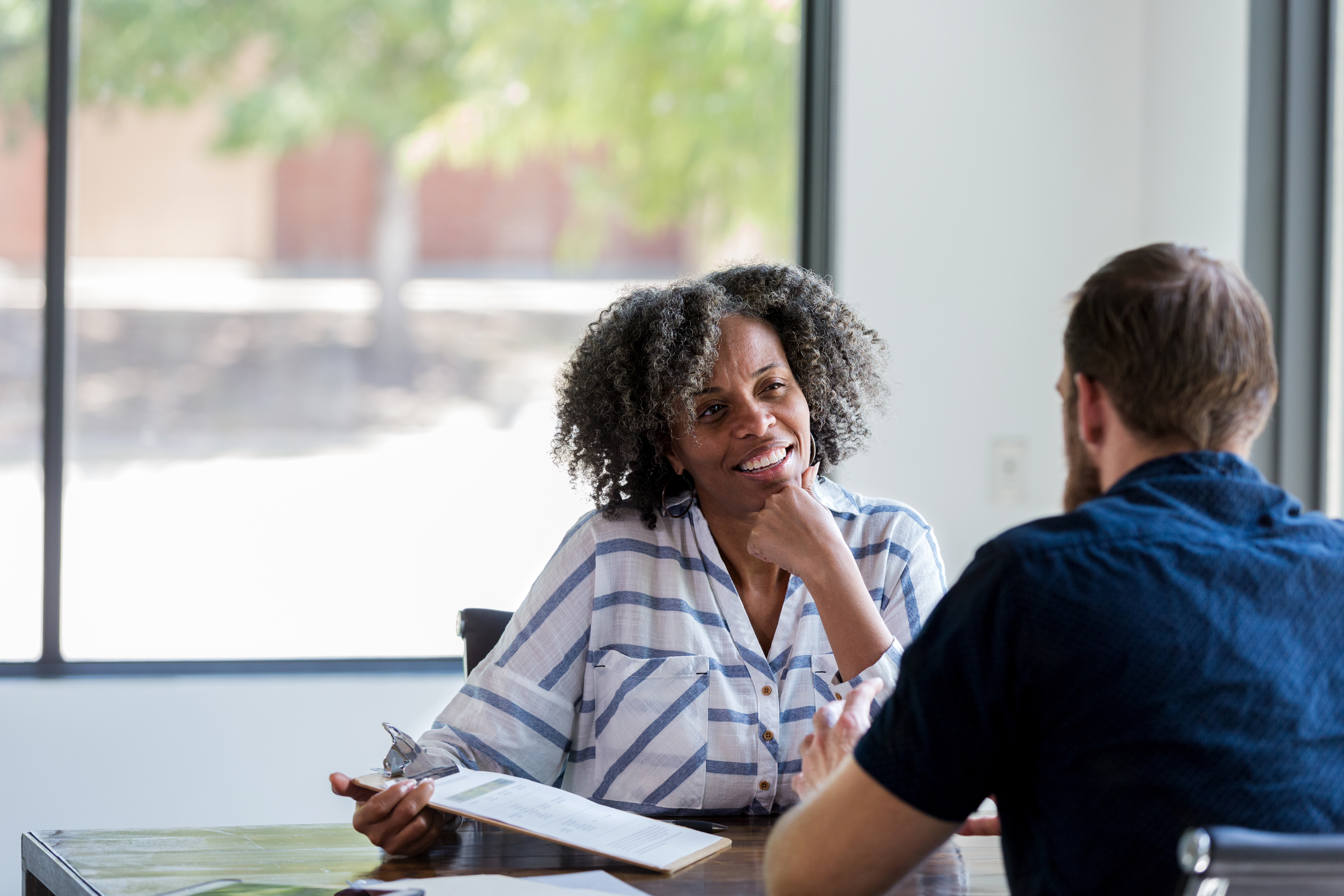 Women interviewing a man holding his CV and smiling across the table