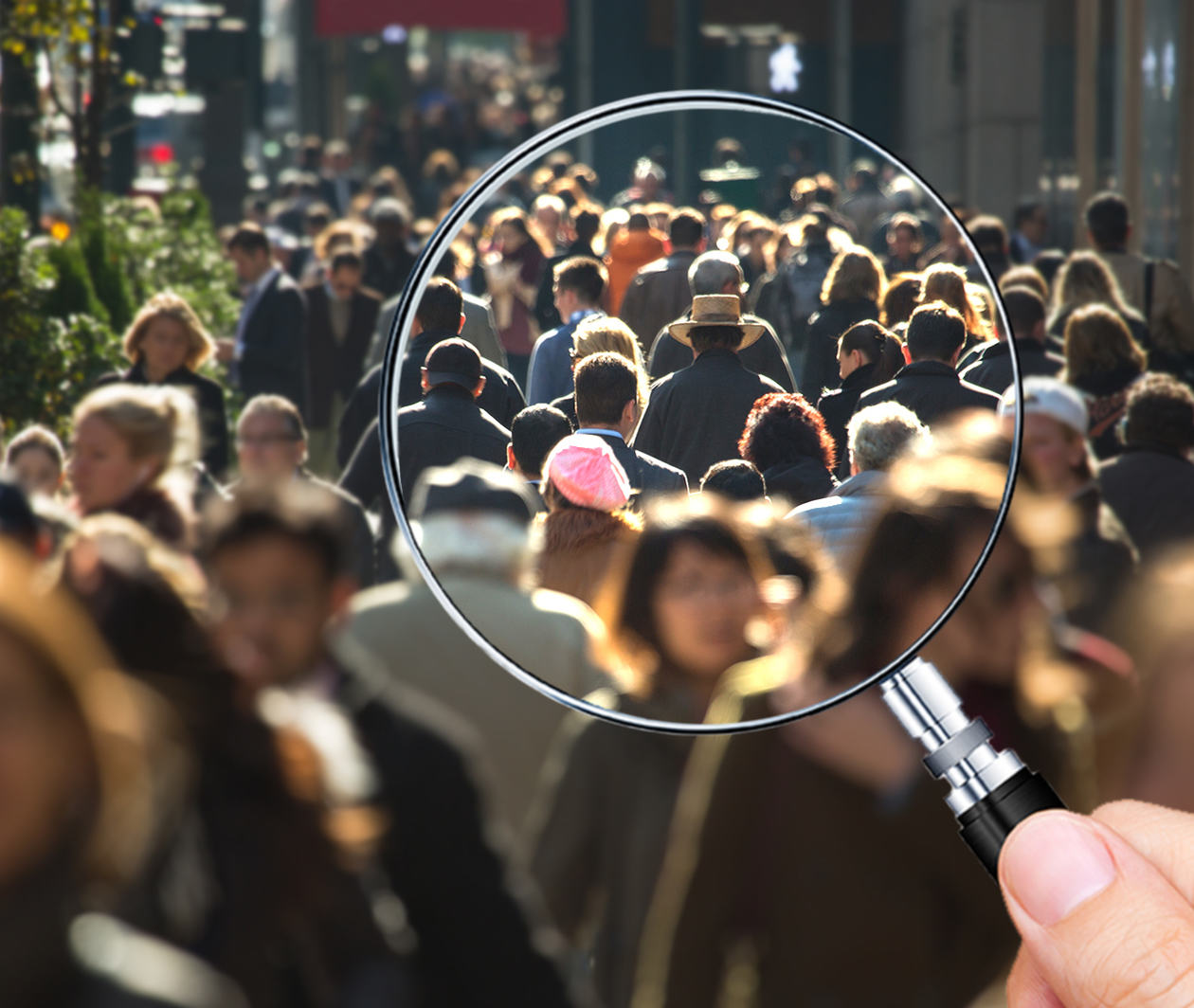 A handheld magnifying glass held over an image of people