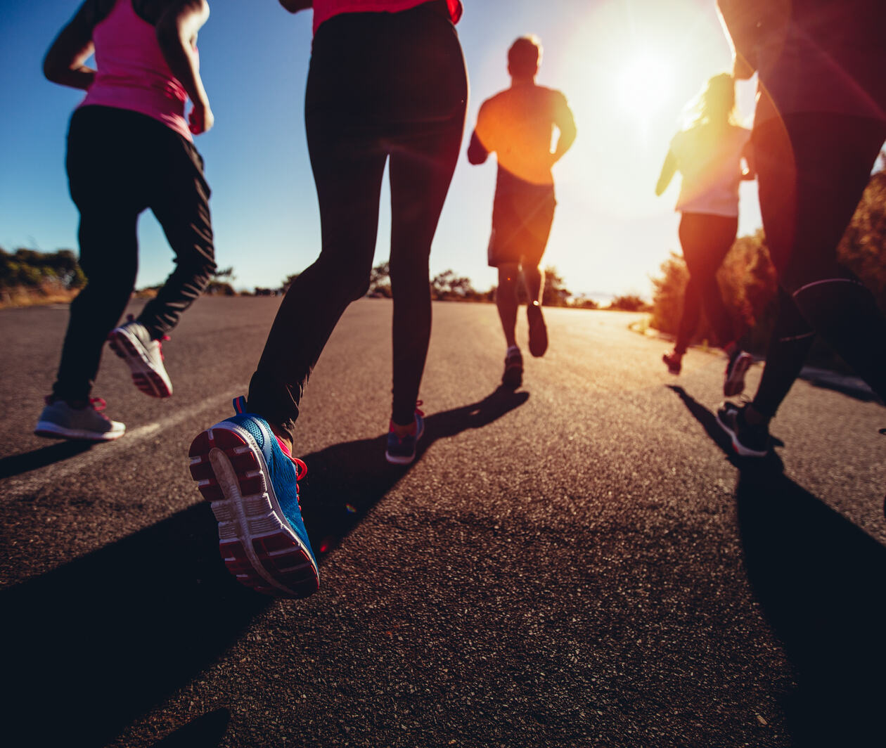 low angle back view of a group of friends jogging outdoors exercise together to promote brain health