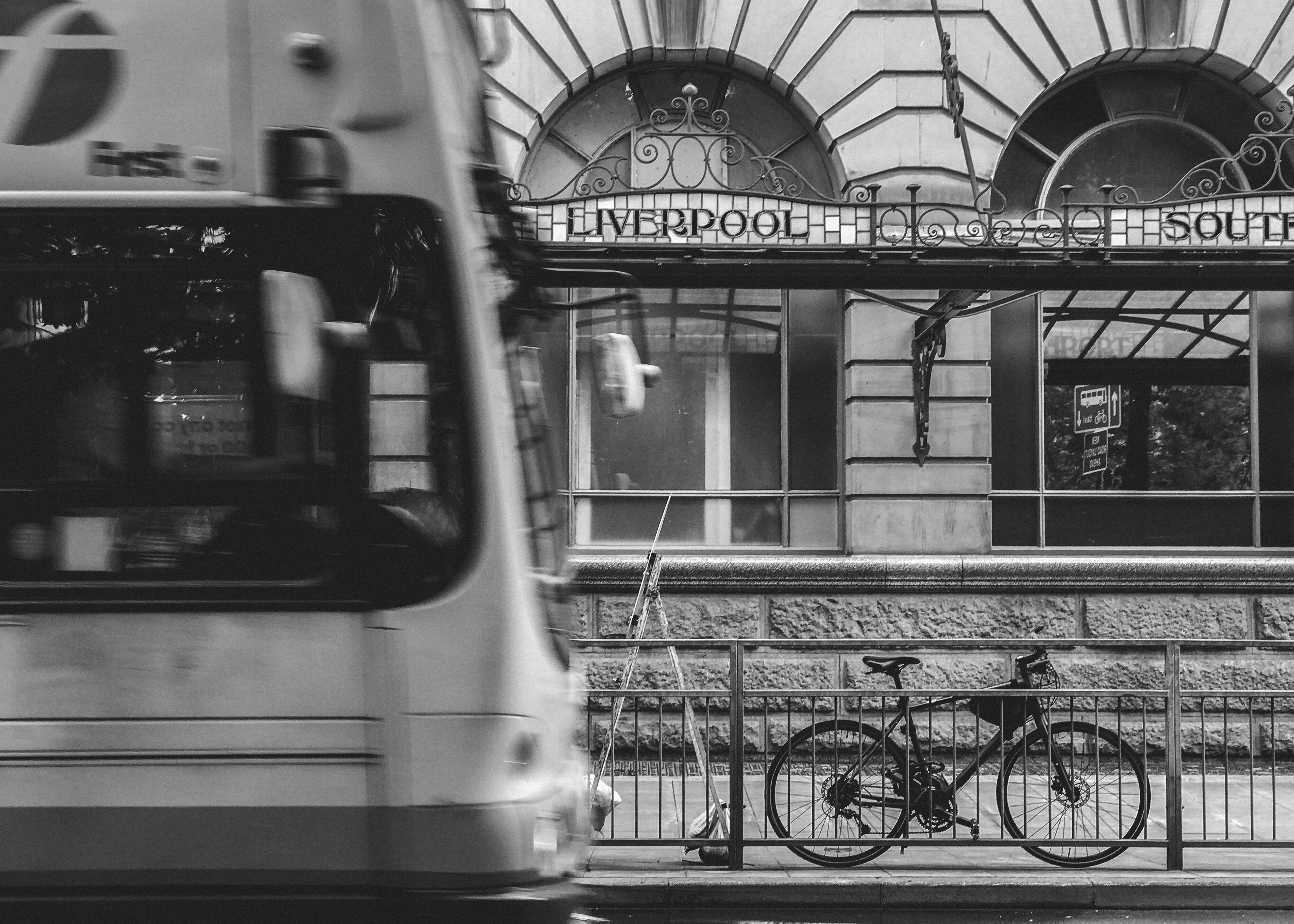 Bus passing a bicycle locked to railings