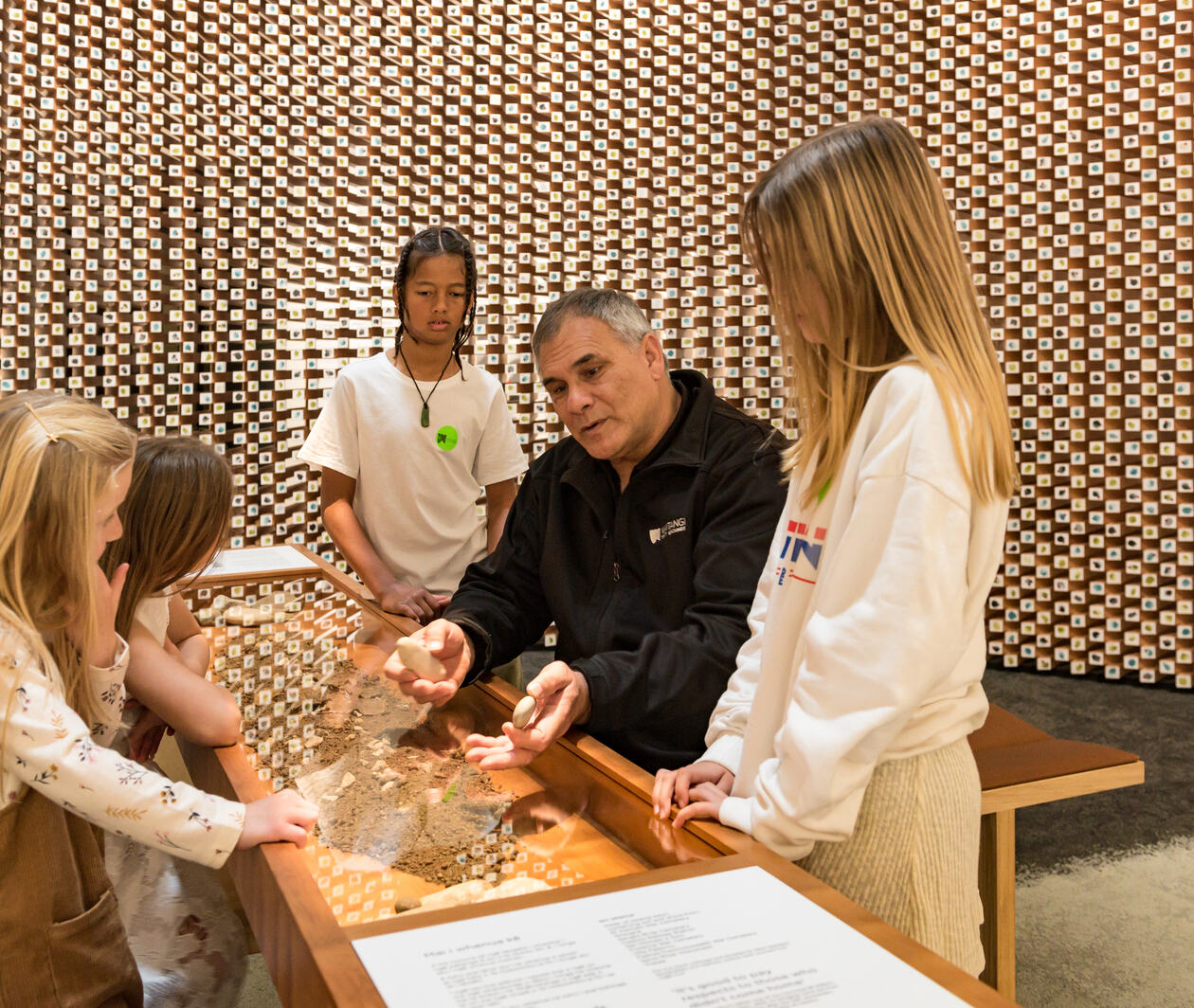 An educator and students exploring artefacts in He Whakamaumaharatanga at the Waitangi Treaty Grounds.