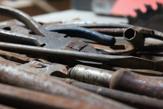 A selection of rusted tools on a bench