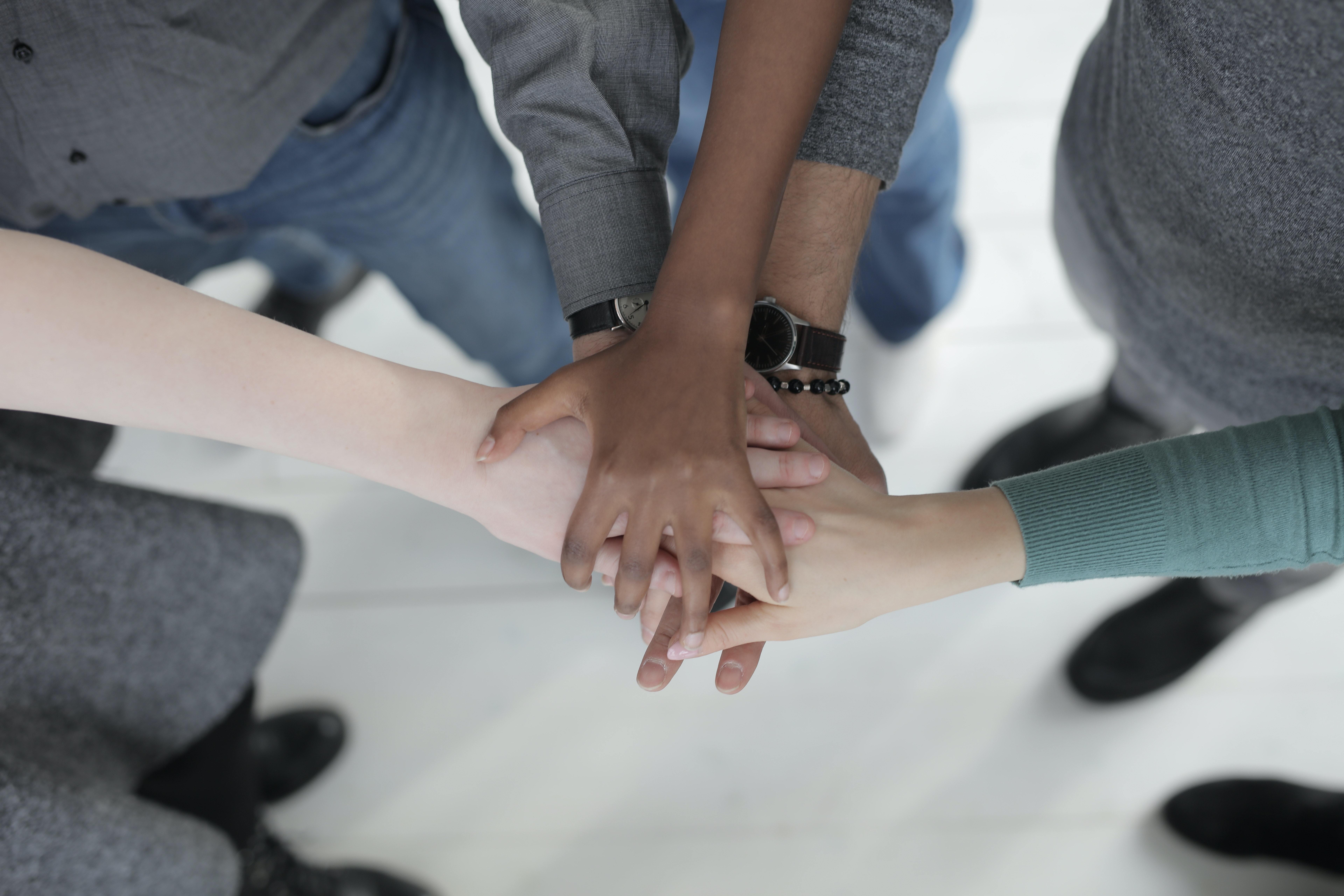 hands from people of different ethnicities reaching together