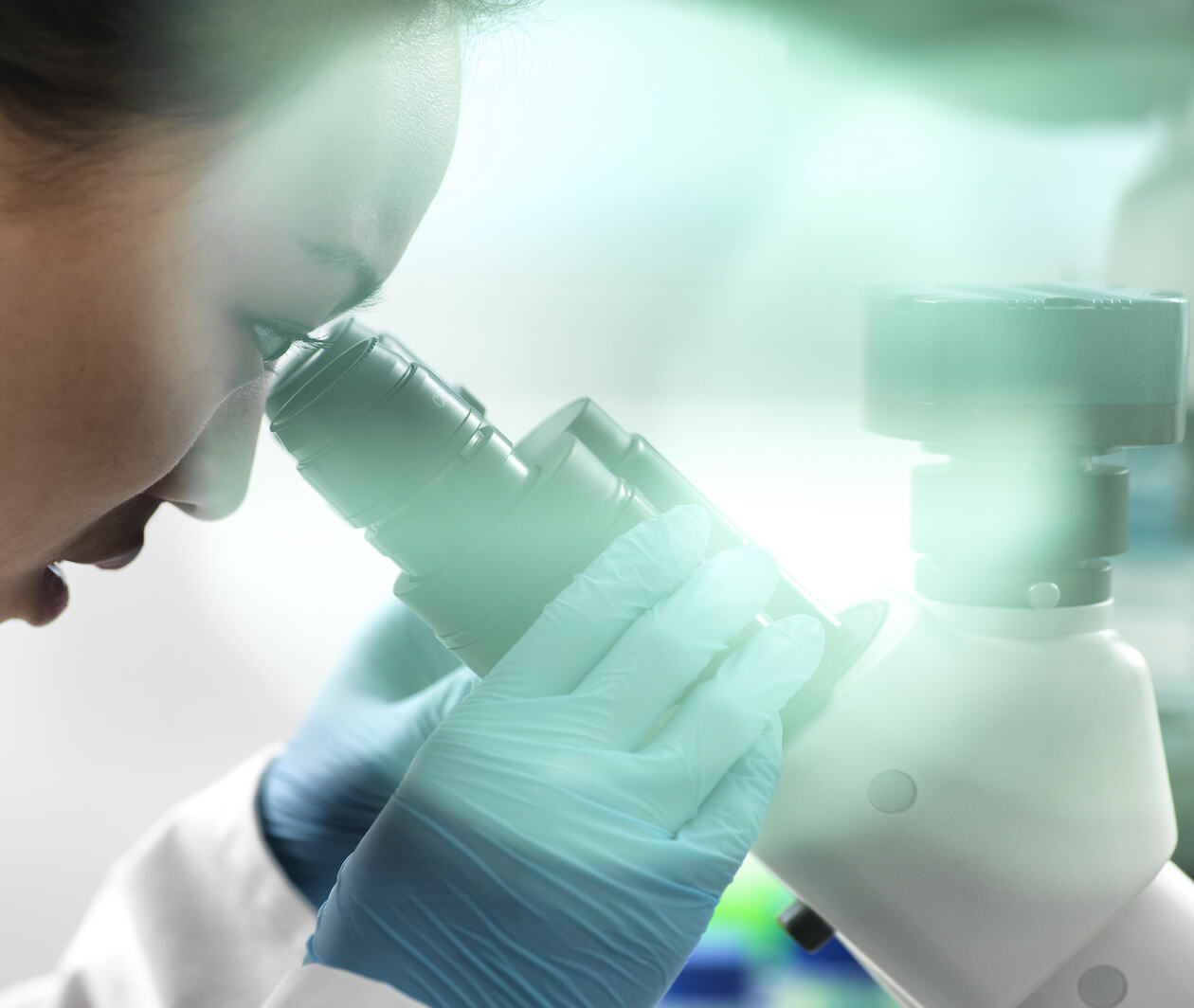 A close up shot of a female scientist conduction clinical research, as she looks down a microscope, studying rare diseases