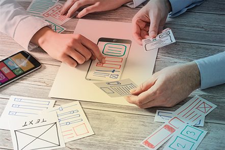 Dos personas haciendo un guión gráfico del diseño de una aplicación en trozos de papel